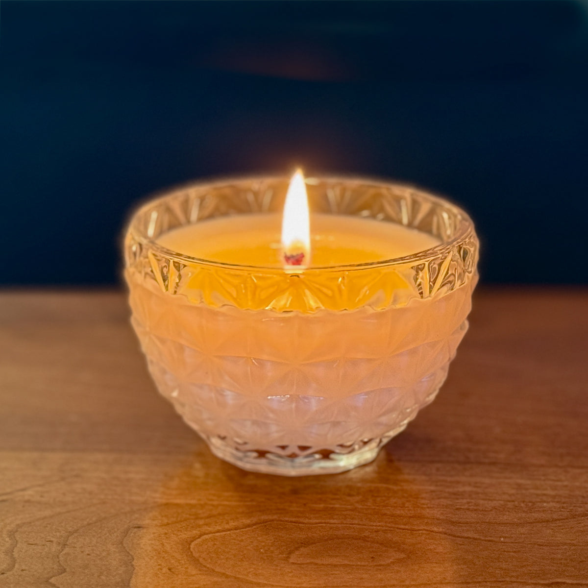 A burning unscented candle on a wood surface by Unscented Candle Company