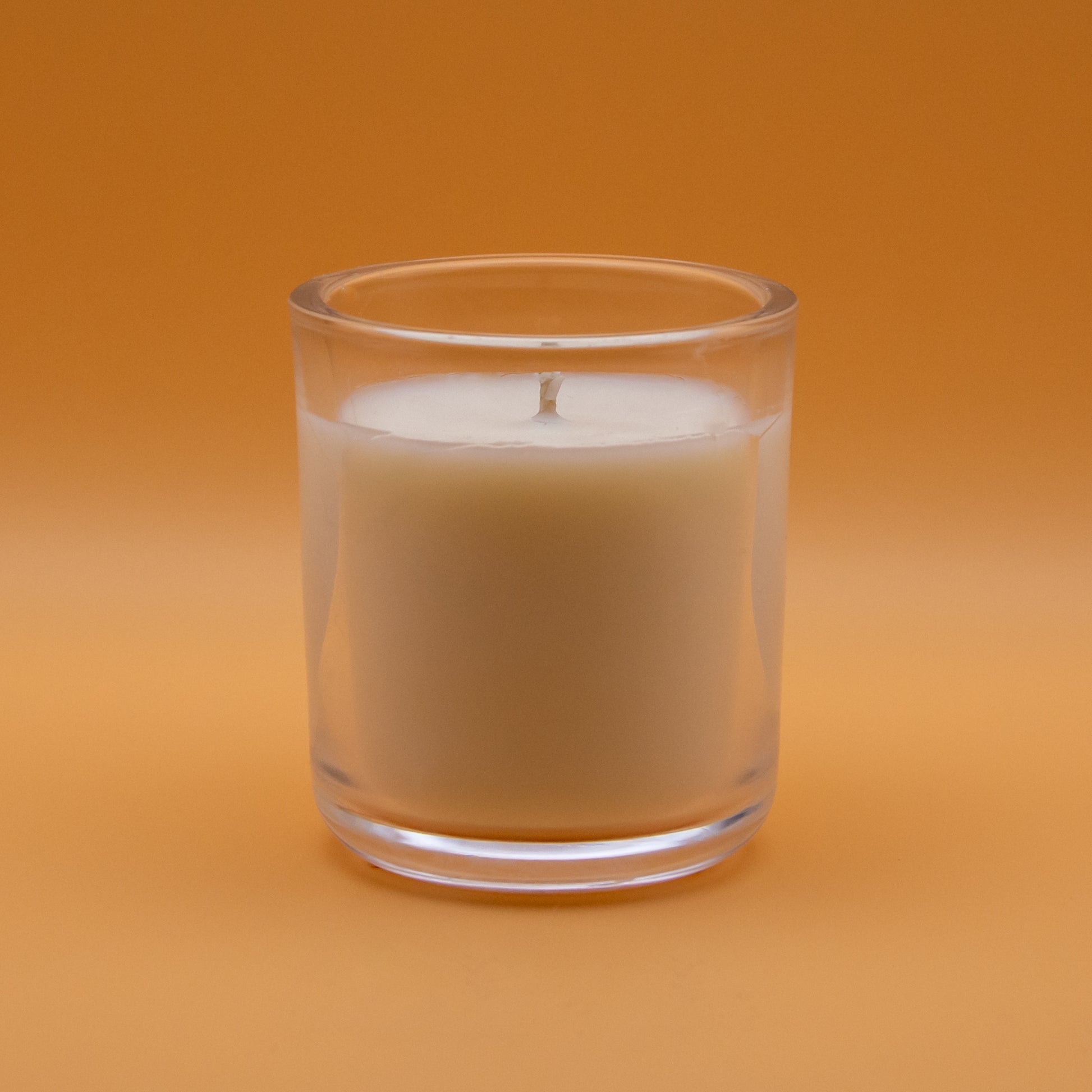 The Unscented Candle Company votive candle on peach background