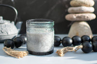 Lotus embossed unscented candle, surrounded by black beads and a teapot