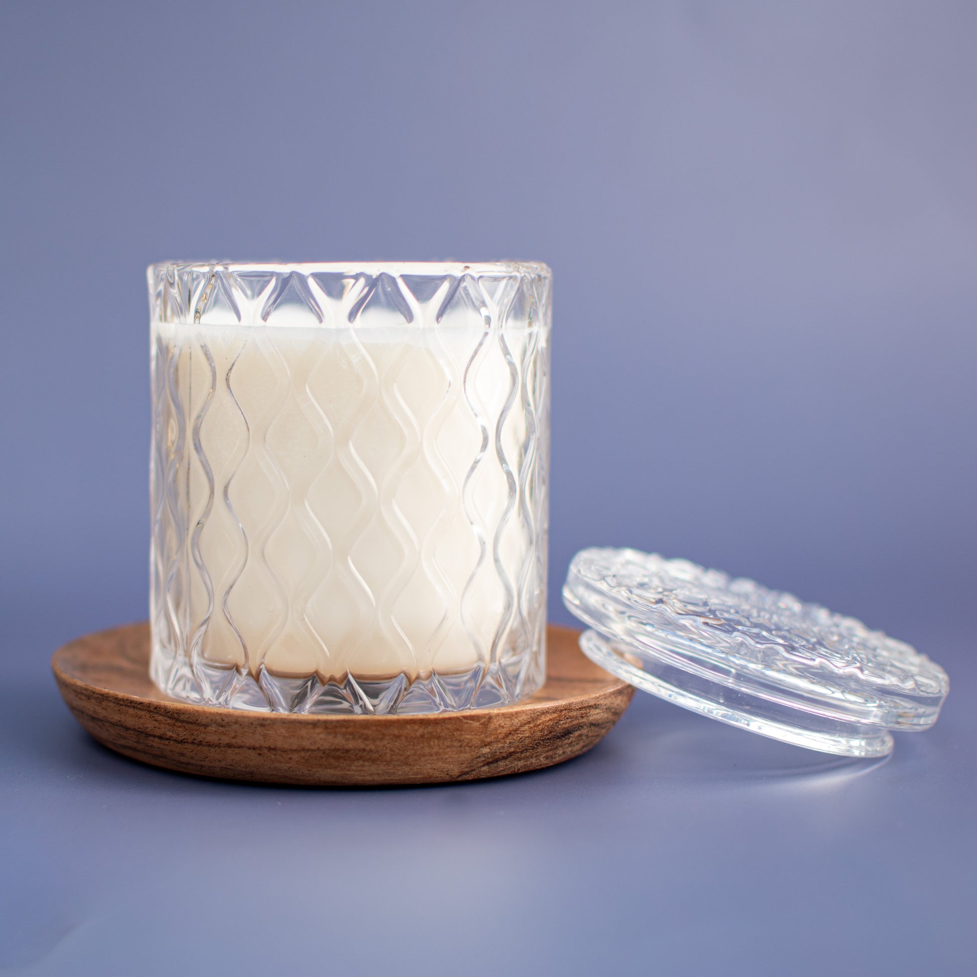 The Vienna fragrance free soy candle in embossed glass vessel with lid on wood coaster